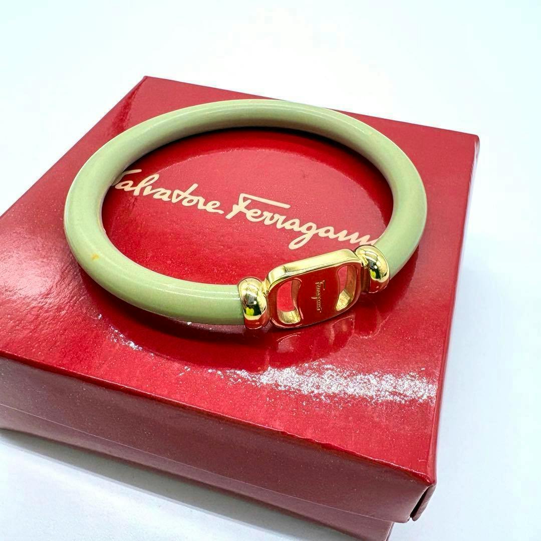 Green Ferragamo Vara bangle bracelet with gold hardware shown on a red Salvatore Ferragamo box.