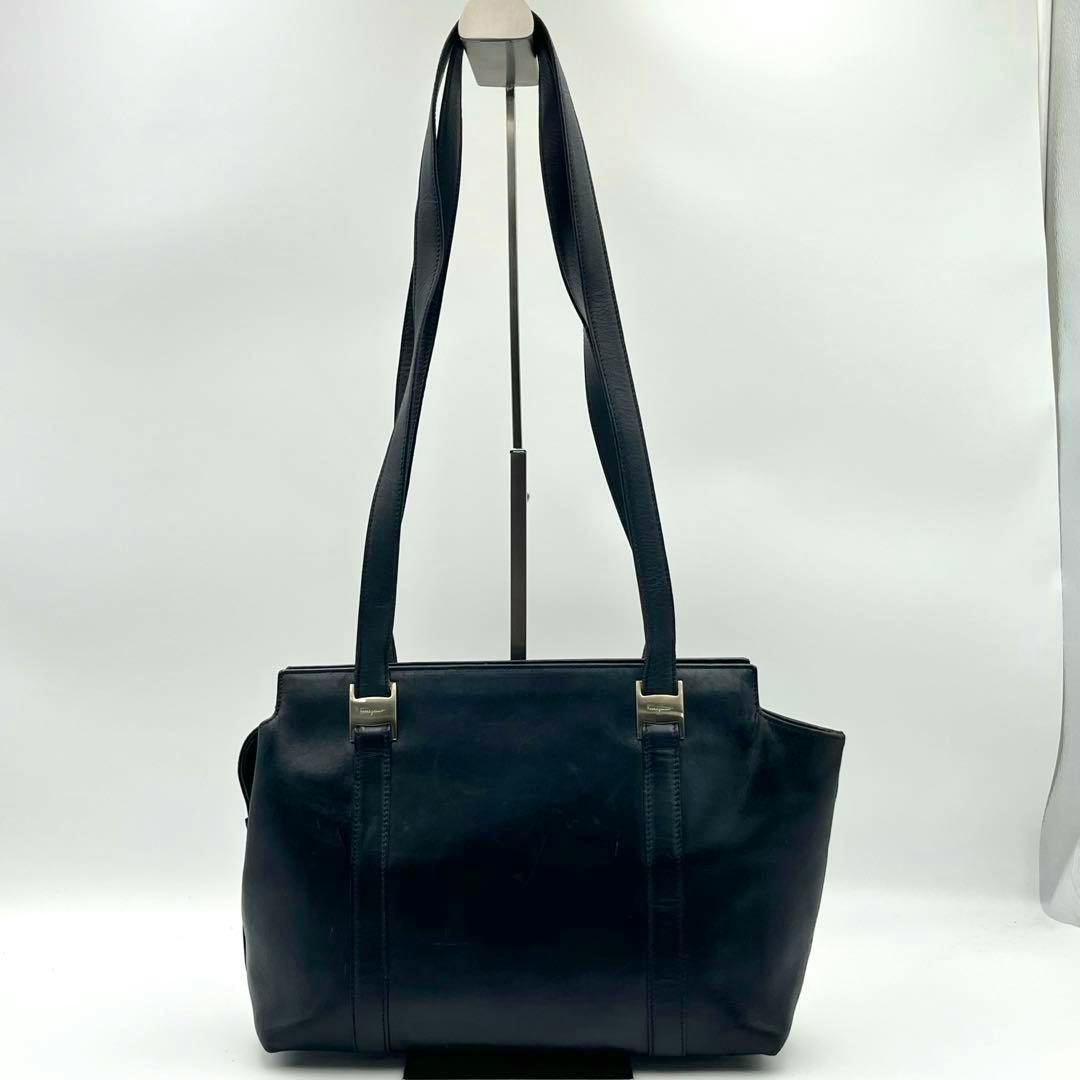 Black Ferragamo leather shoulder bag with long straps and metal Vara-logo hardware against a white background.