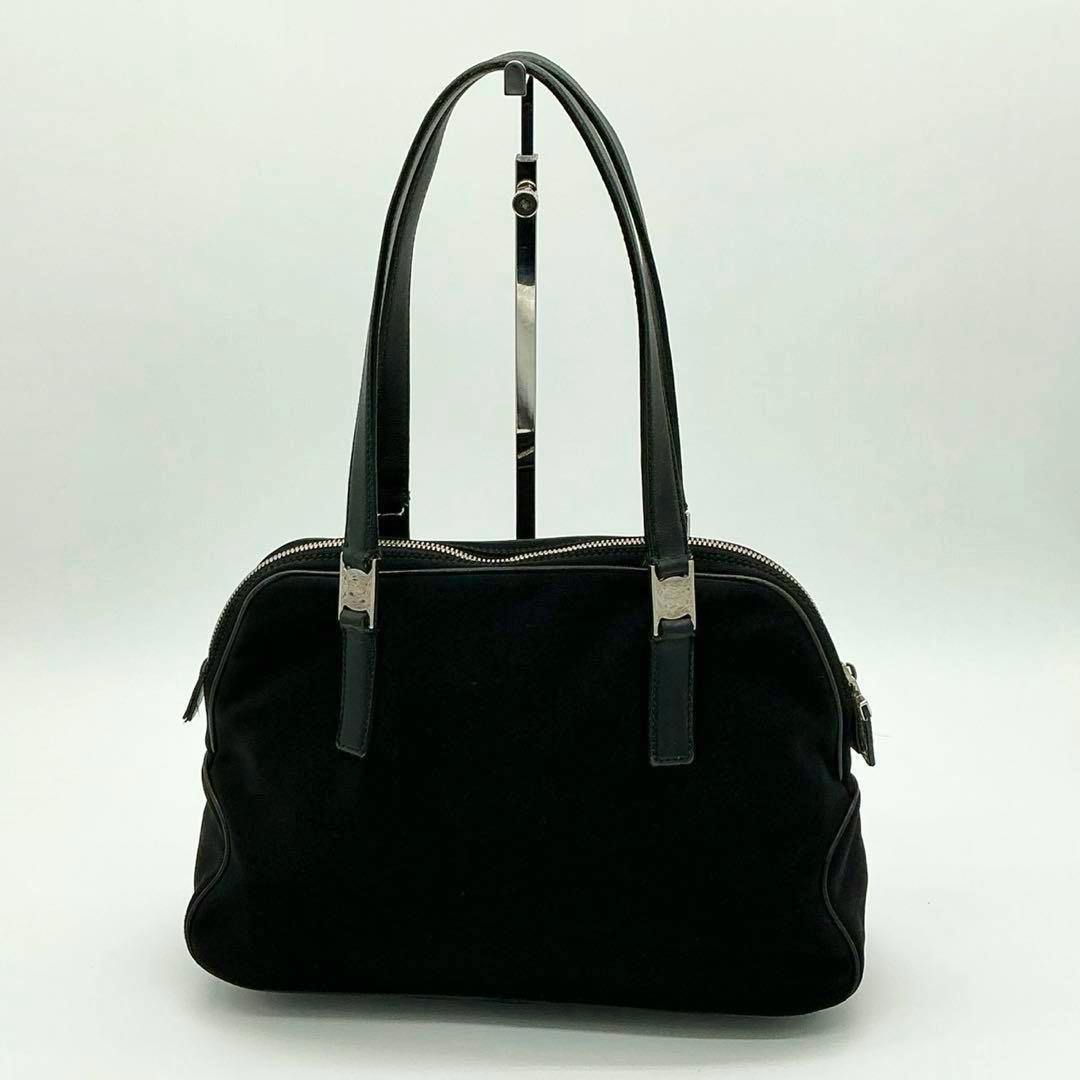 Front view of a black satin nylon handbag with leather handles and a silver zipper.