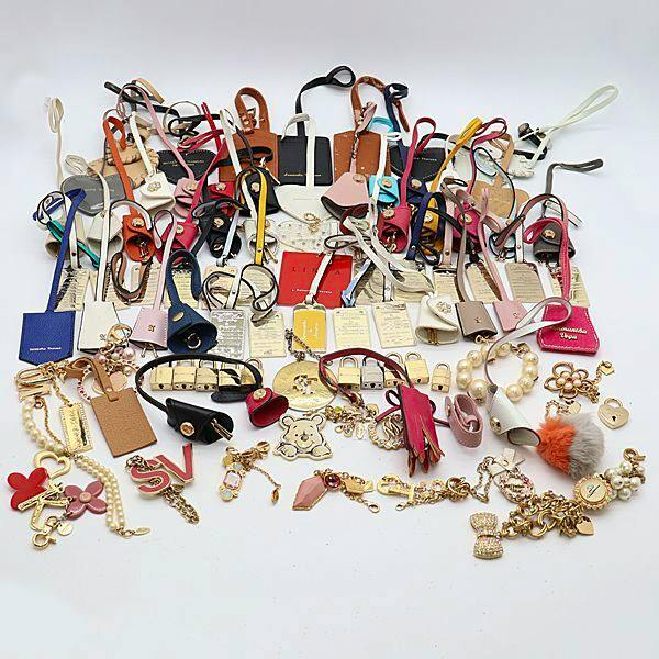 A large assortment of Samantha Thavasa charms and keyrings laid out on a white background, showing various leather straps, metal tags, and decorative pendants.