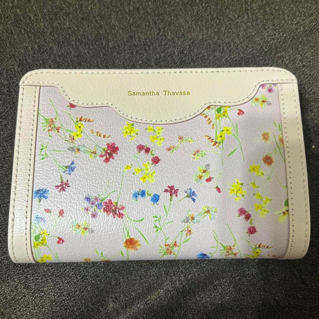 Close-up of the Samantha Thavasa floral-patterned bi-fold wallet with white trim and gold logo.