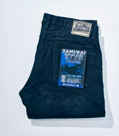 Folded Samurai Jeans men's denim pants (black on indigo) showing back-pocket tag and leather patch.