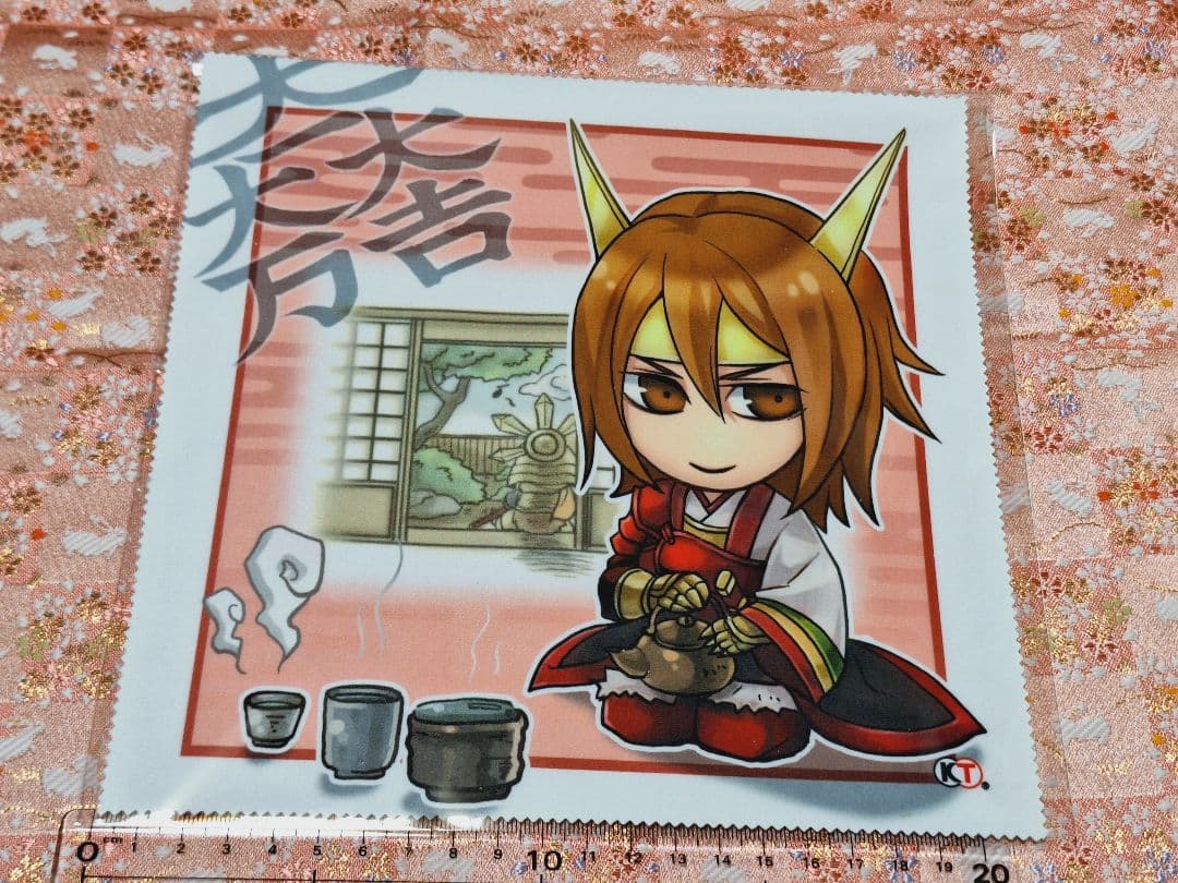 Polyester cleaner cloth laid flat showing a chibi illustration of Ishida Mitsunari (石田三成) from Sengoku Musou 3 with a small tea set and a measuring ruler visible.