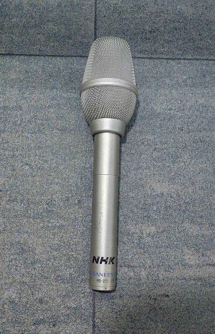 Silver SANKEN MO-211 dynamic microphone with NHK logo shown upright on a textured background.