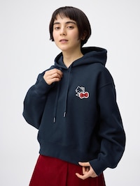 Woman modeling a navy heavyweight short hooded sweatshirt for women with a small Sanrio character patch on the chest.