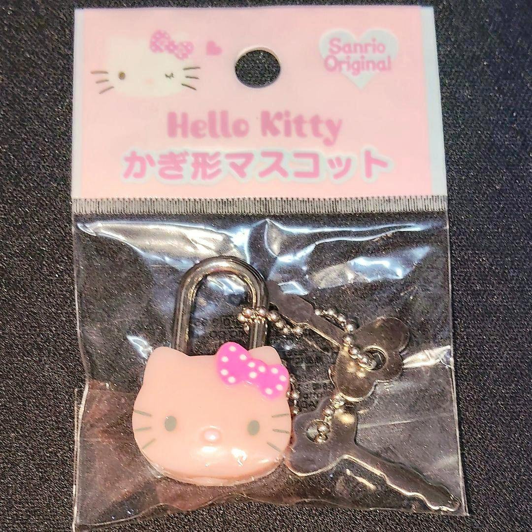 Front view of a packaged Hello Kitty key-shaped mascot keychain (plastic) with a pink polka-dot bow and attached metal keys.