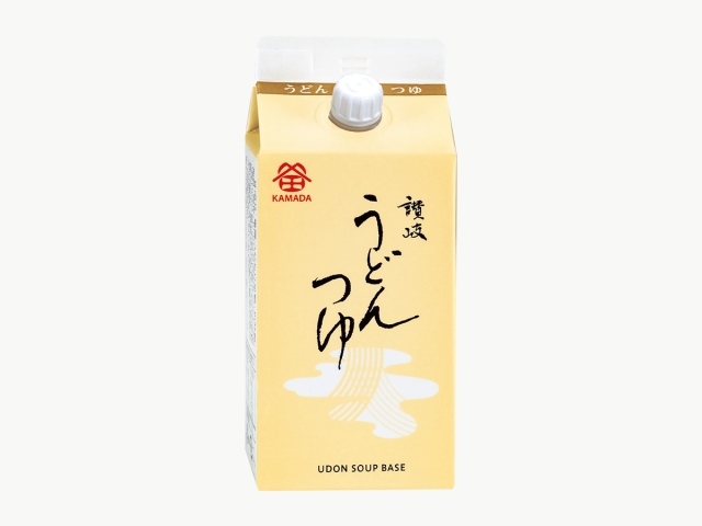 A yellow carton of 讃岐 うどんつゆ (udon soup broth) with a white screw cap and Japanese text on the front.