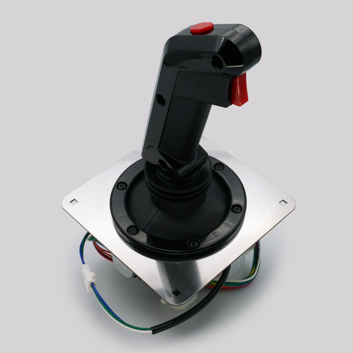Black electronic analogue joystick lever with a red trigger mounted on a square metal baseplate with exposed wires.