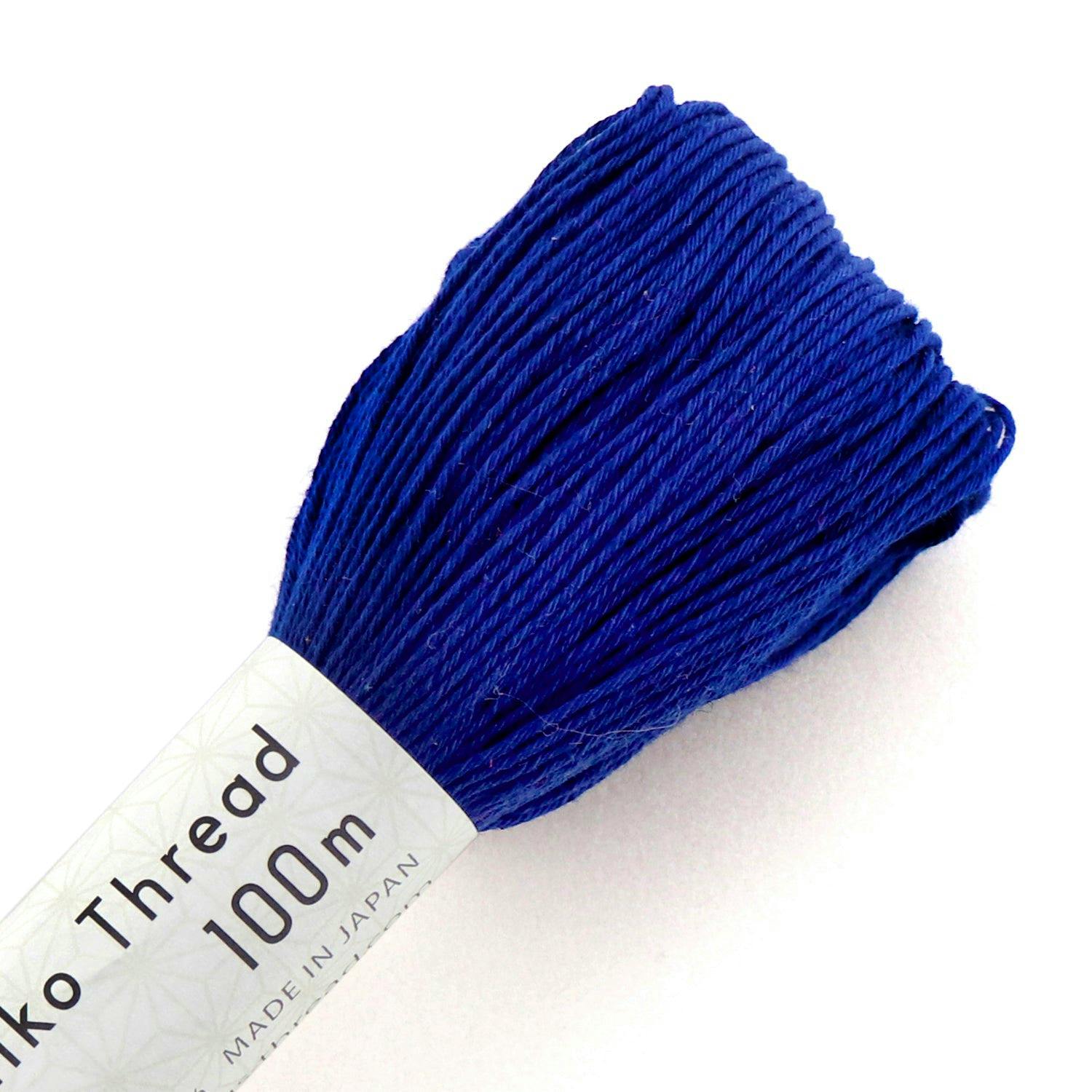Close-up of a blue sashiko cotton thread skein showing its white label with 100m visible.