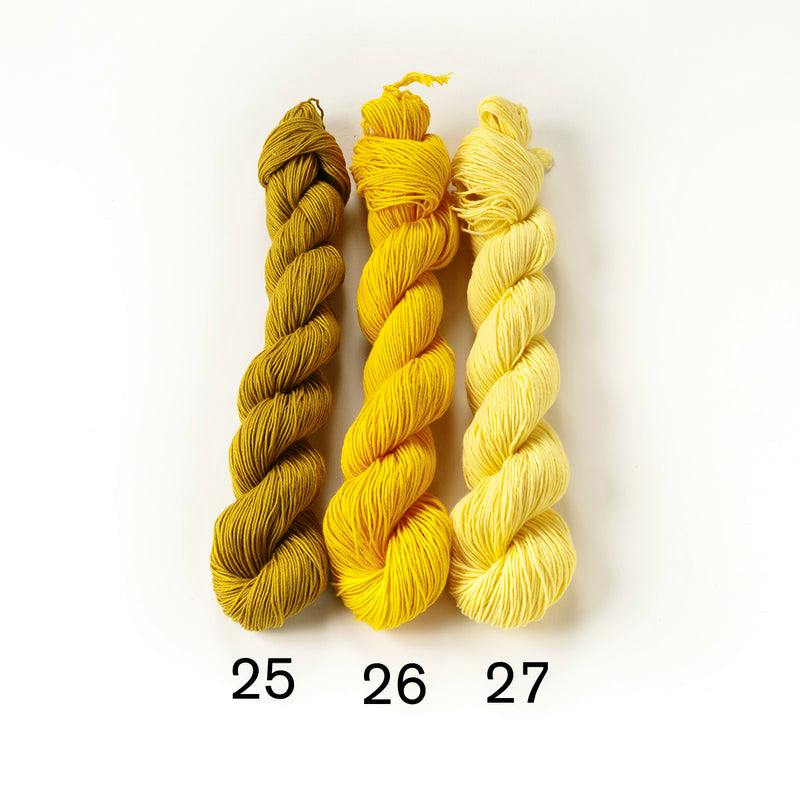 Three skeins of yellow cotton sashiko thread labeled 25, 26, and 27 on a white background.