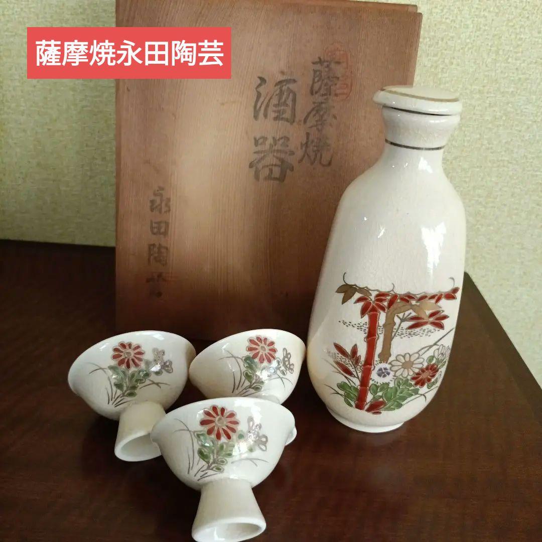 Satsuma Nagata porcelain sake set showing one tokkuri and three ochoko cups with the wooden storage box behind.