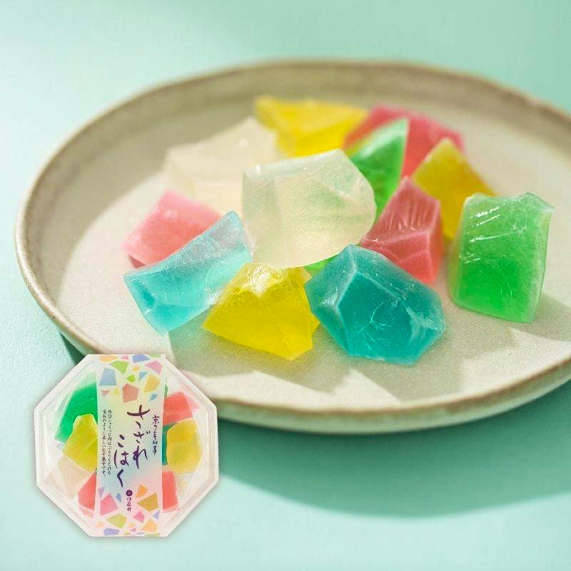 A plate showing assorted colorful さざれこはく sugar candies with the product's packaged container visible in the corner.