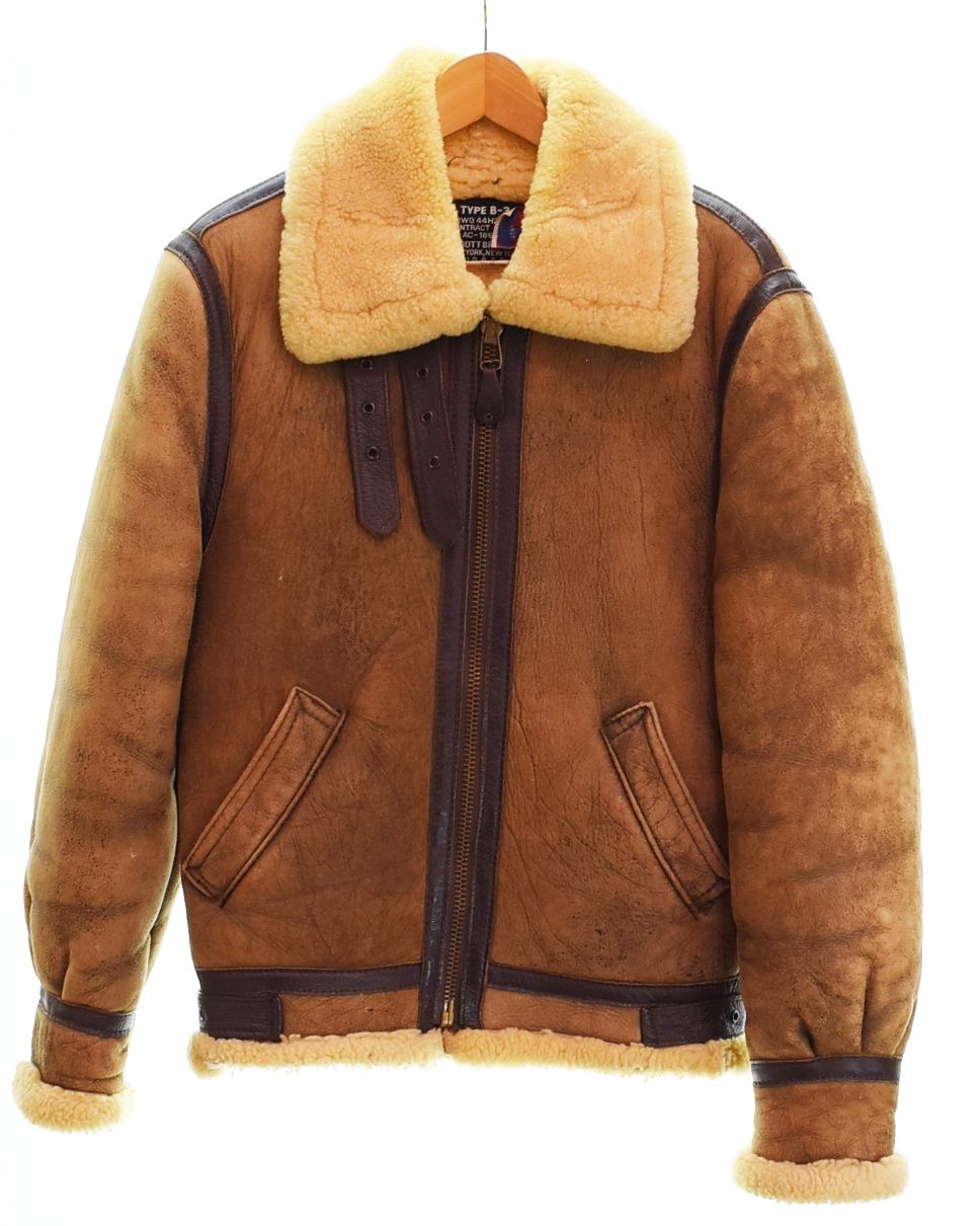 Front view of a beige Schott B-3 vintage shearling (lambskin) flight jacket on a hanger.