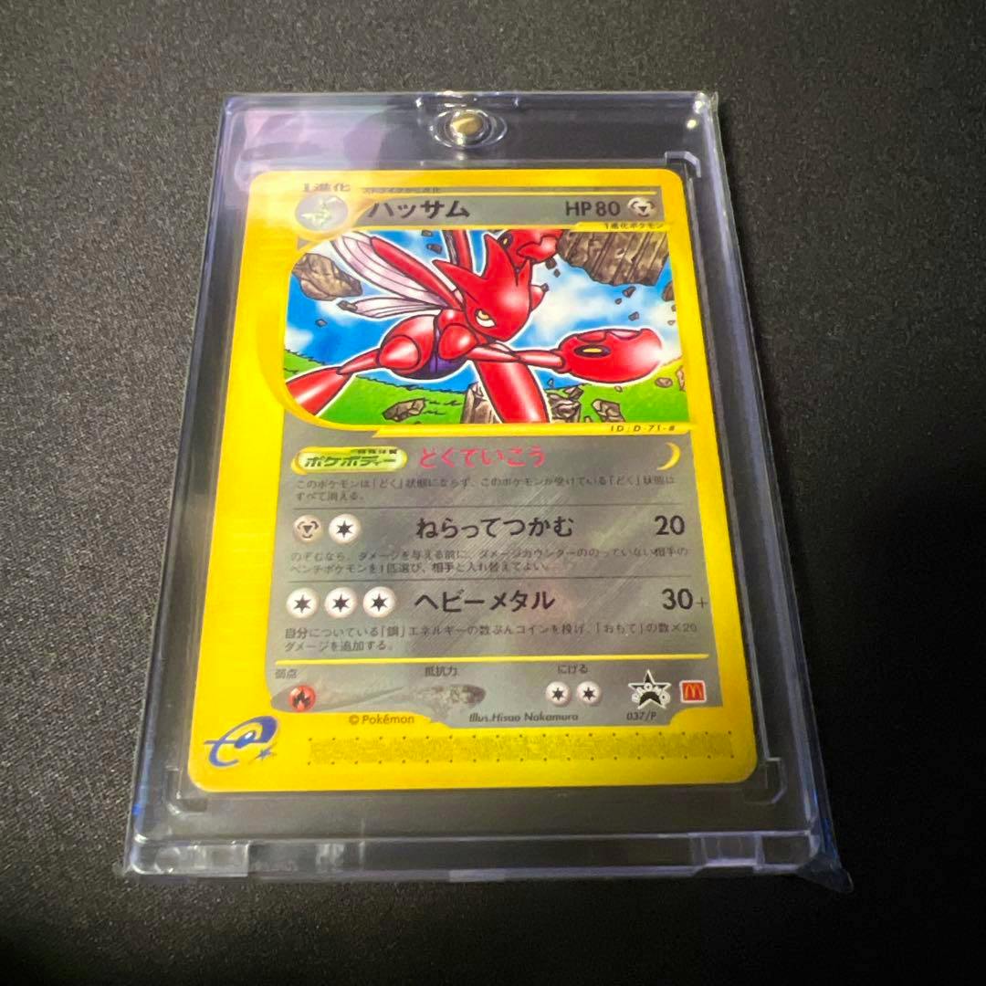Front of the ハッサム PROMO P - eプロモカード 037/P trading card visible in a clear plastic sleeve on a dark surface.