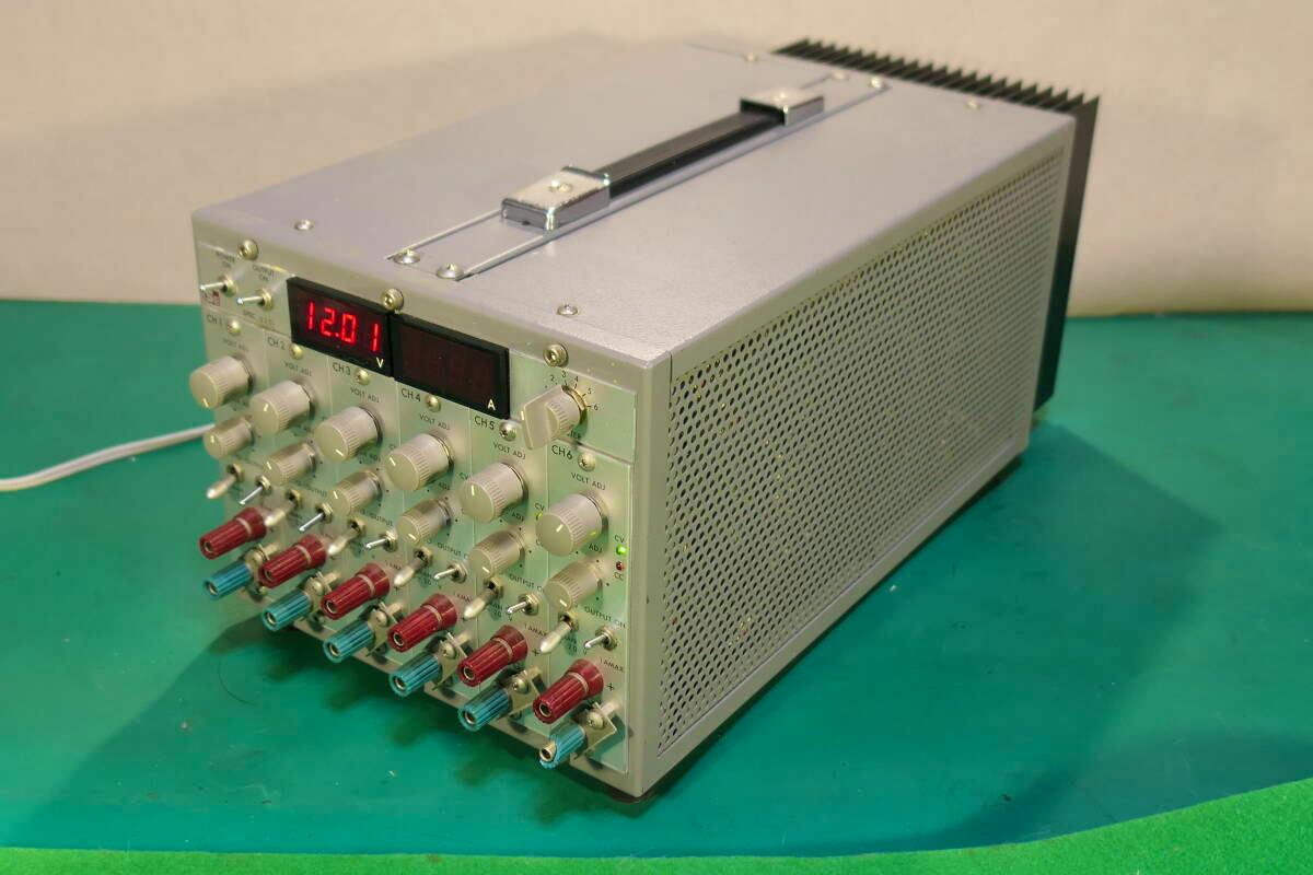 Front-left angled photo of the SE SPEC 6201 six-channel DC power supply unit showing control knobs, output terminals, and a digital voltage display.