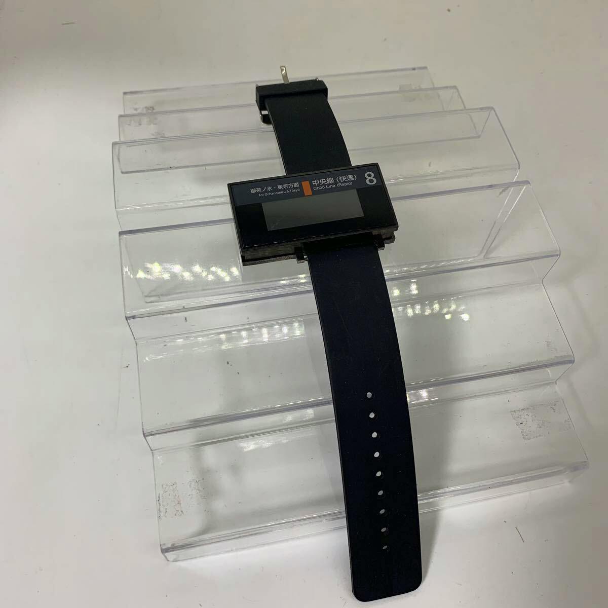 Rectangular SEAHOPE electric-display watch showing Chuo Line graphics with a black strap on a clear plastic display stand.