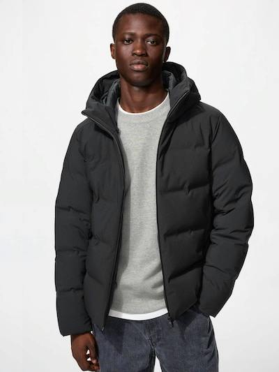 Male model wearing a black seamless down parka with hood and a visible front zipper.