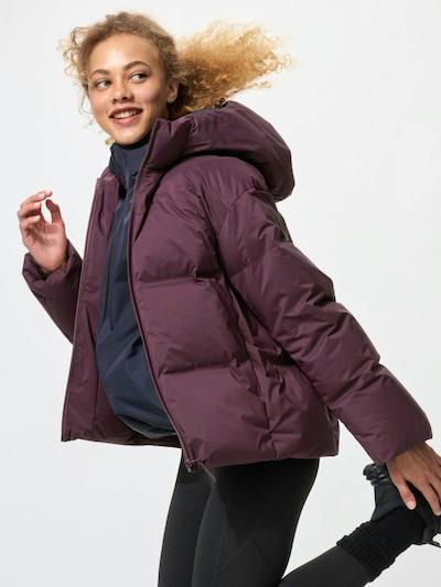 Person wearing the seamless down short coat in purple with a hood, shown in a dynamic side pose.