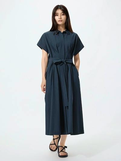 Front view of a woman wearing a navy seersucker shirt dress with short sleeves and a waist tie.