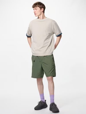 Male model wearing the men's nylon shorts in green, shown full-length against a white background.