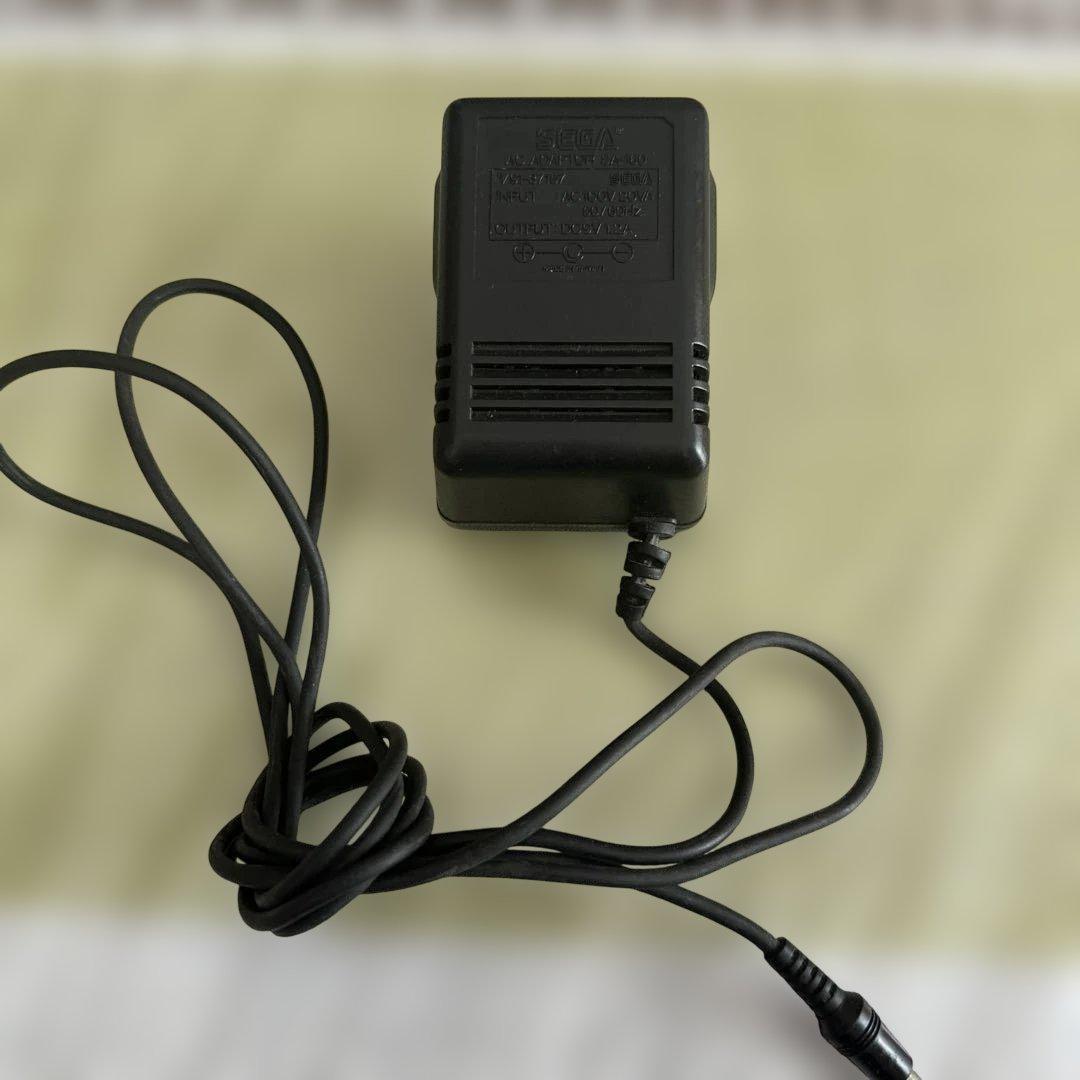 SEGA AC adapter SA-160 with attached cable placed on a light background.