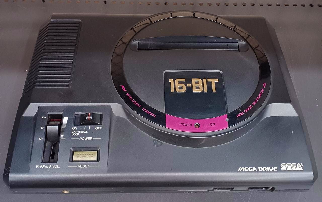 Close-up top view of the Mega Drive game console showing the 16-BIT badge, cartridge area, power and reset controls, and SEGA branding.