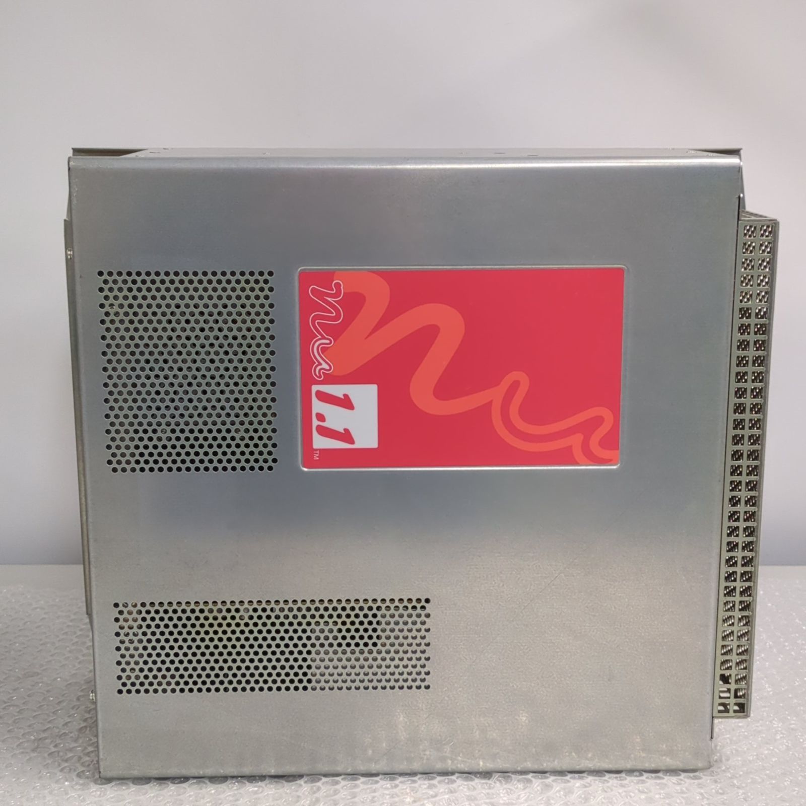 Metal SEGA arcade PCB housing labeled "Nu1.1" with ventilation holes and an edge connector visible.
