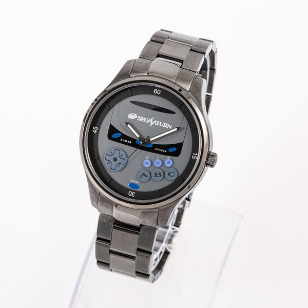 Metal wristwatch with a Sega Saturn themed dial and metal bracelet shown on a clear stand against a white background.