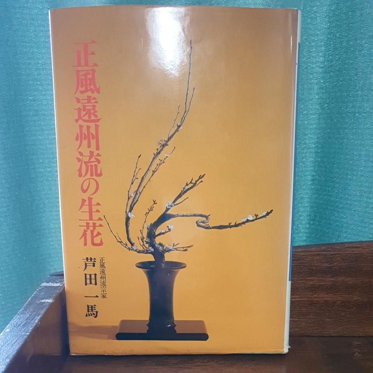 Front cover of a Japanese book showing an ikebana vase with branching stems on an orange background and vertical red Japanese title text.
