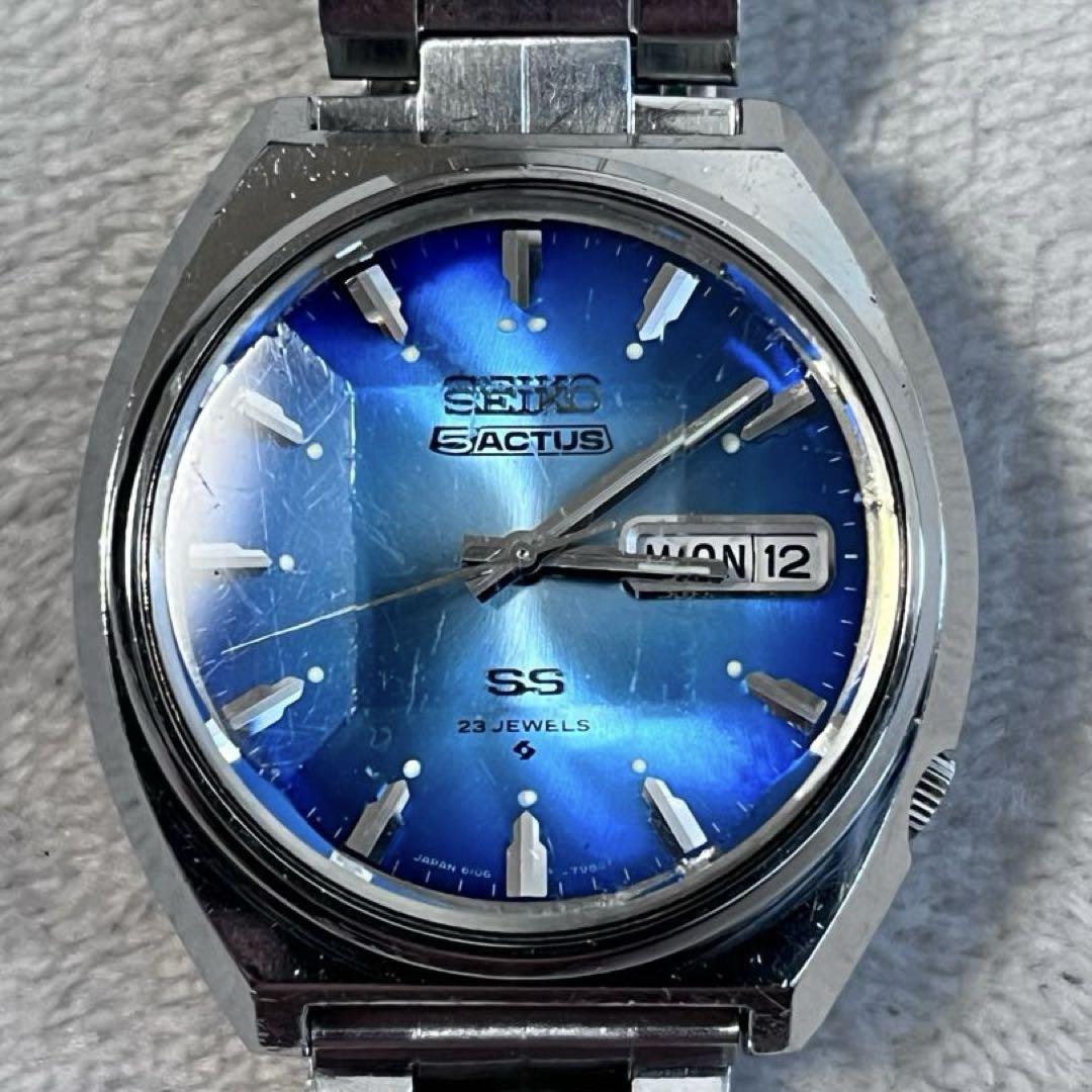 Front view of the SEIKO ACTUS 6106-7700 automatic wristwatch with a blue sunburst dial, day/date window, and a cracked crystal.