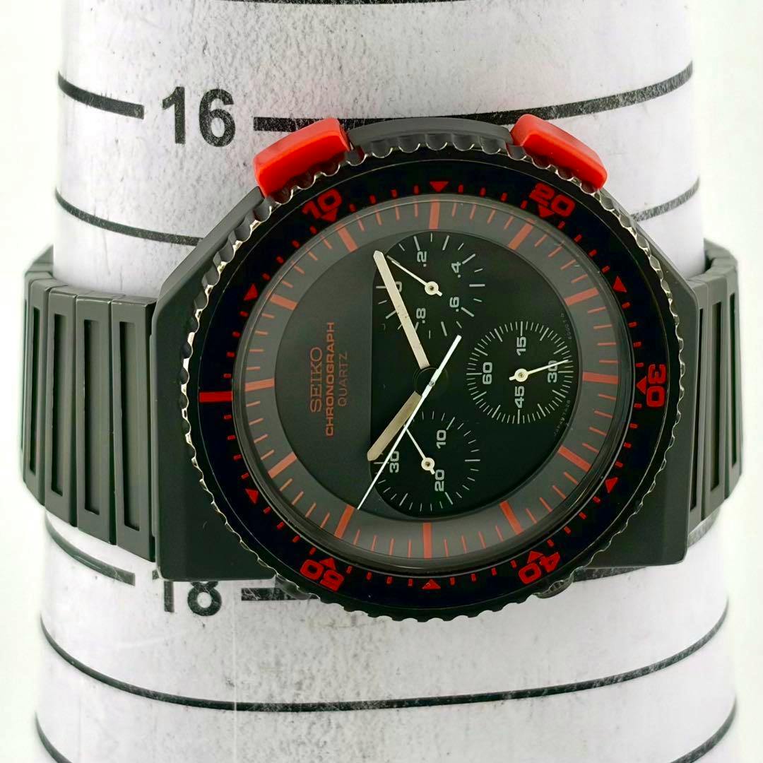 Front view of the SEIKO Chronograph Quartz watch with a black case, red bezel markings, three subdials, and integrated black plastic strap.