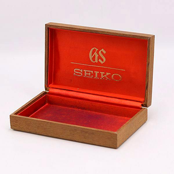 Open brown Seiko watch box with red interior and gold GS and SEIKO logo visible.
