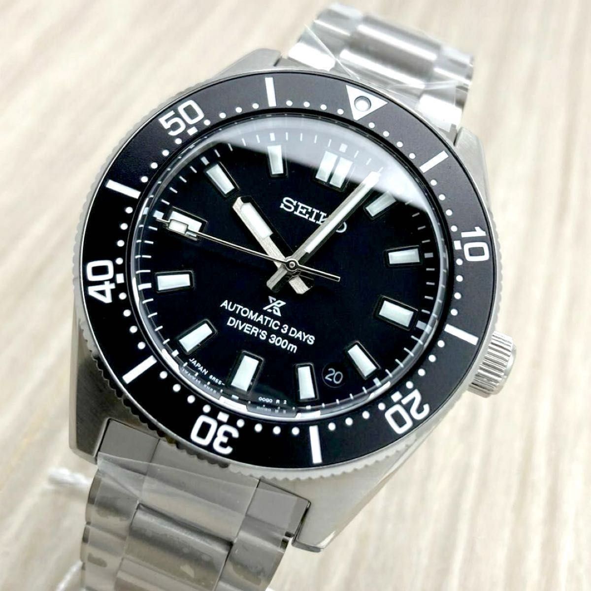 Angled photo of the Seiko Prospex SBDC197 automatic diver wristwatch with a black dial and stainless steel bracelet, showing the bezel, markers, and hands.