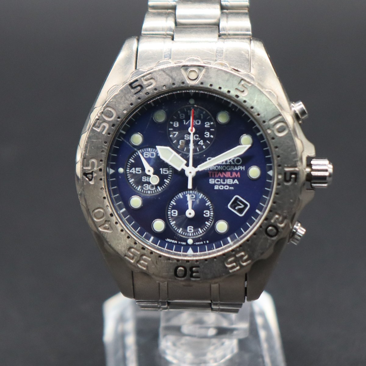 Seiko SCUBA 200M titanium chronograph watch with navy dial and metal bracelet shown on a display stand.