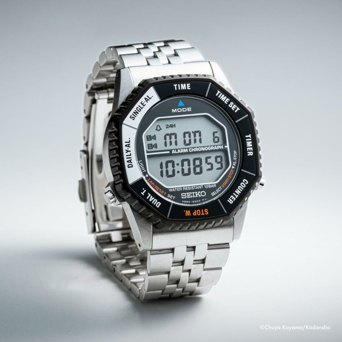 Close-up of a silver metal-cased Seiko digital watch with a stainless steel bracelet showing the LCD display.