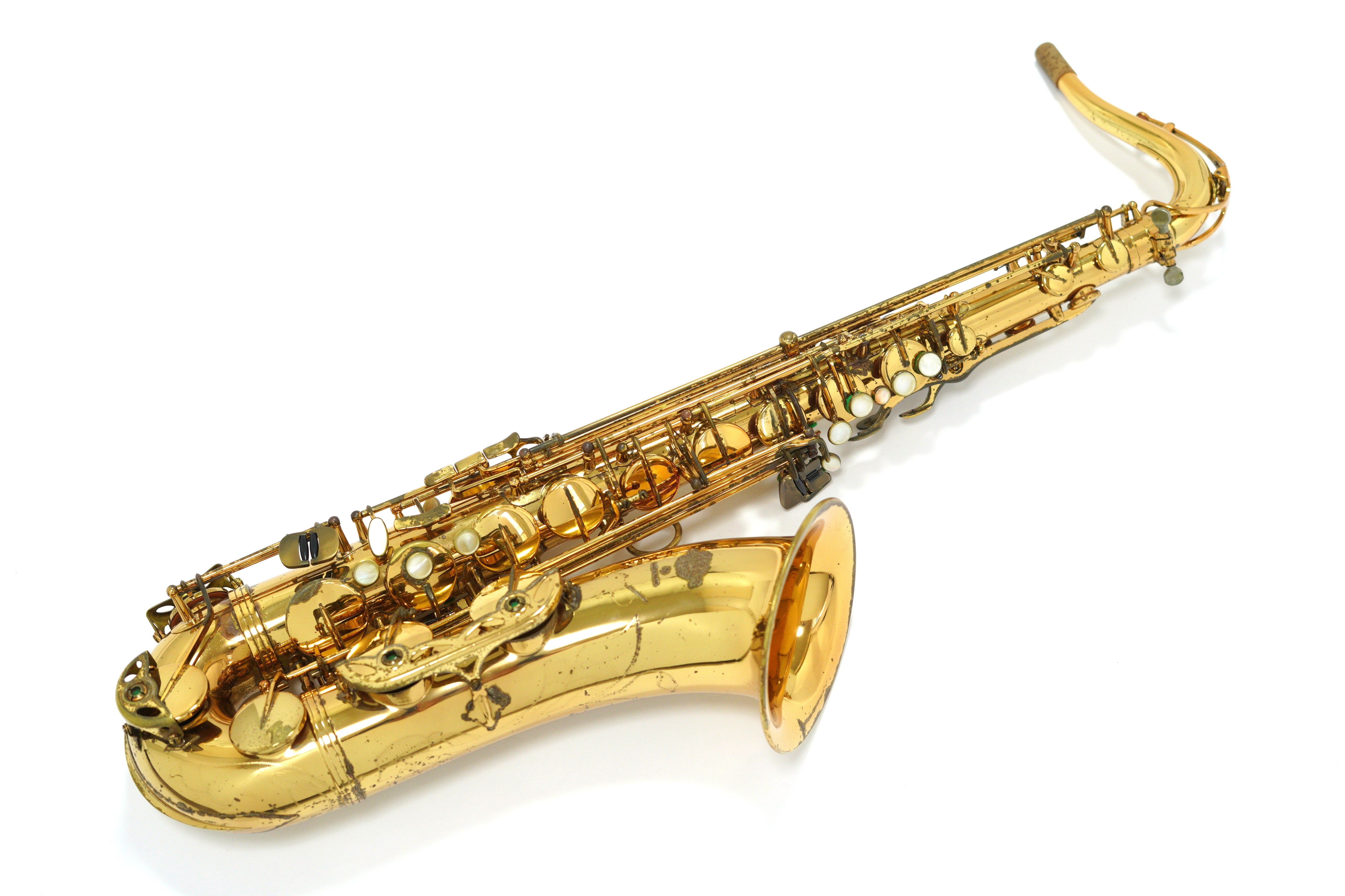A gold tenor saxophone lying on a white background.