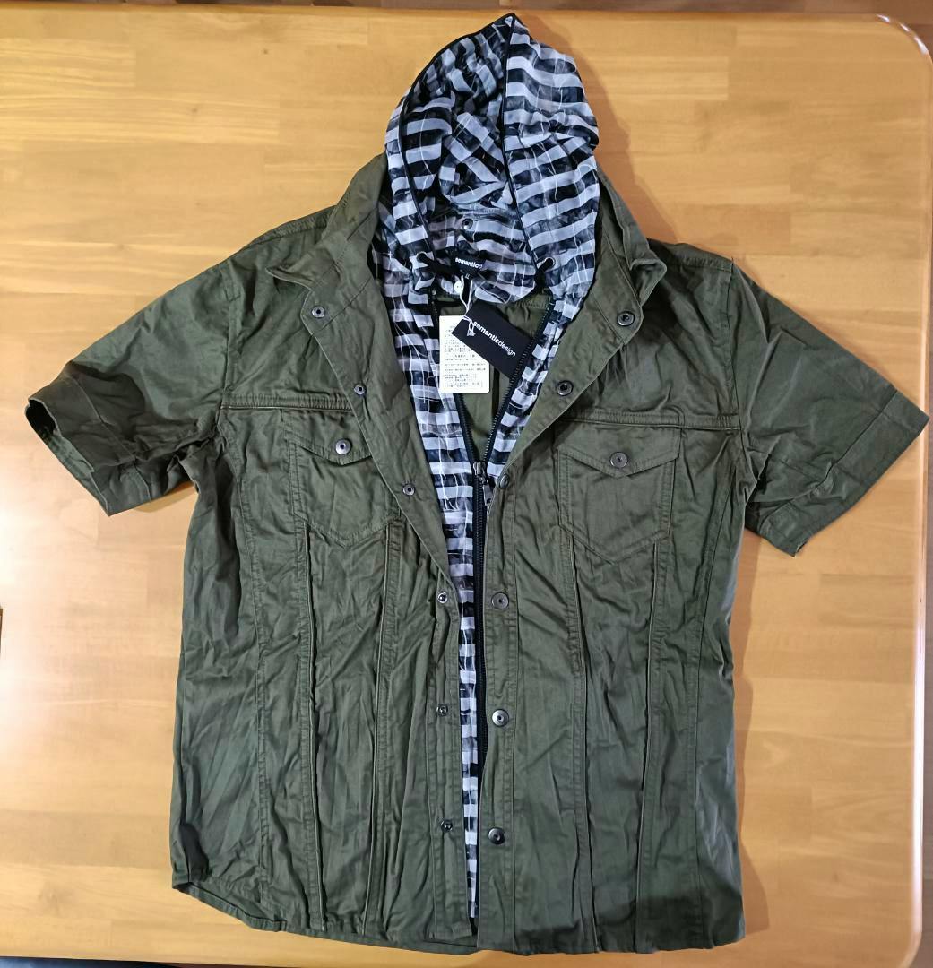 Front view of the semanticdesign fake-layered short-sleeve shirt (LL) in green with a striped hood, laid flat on a table.