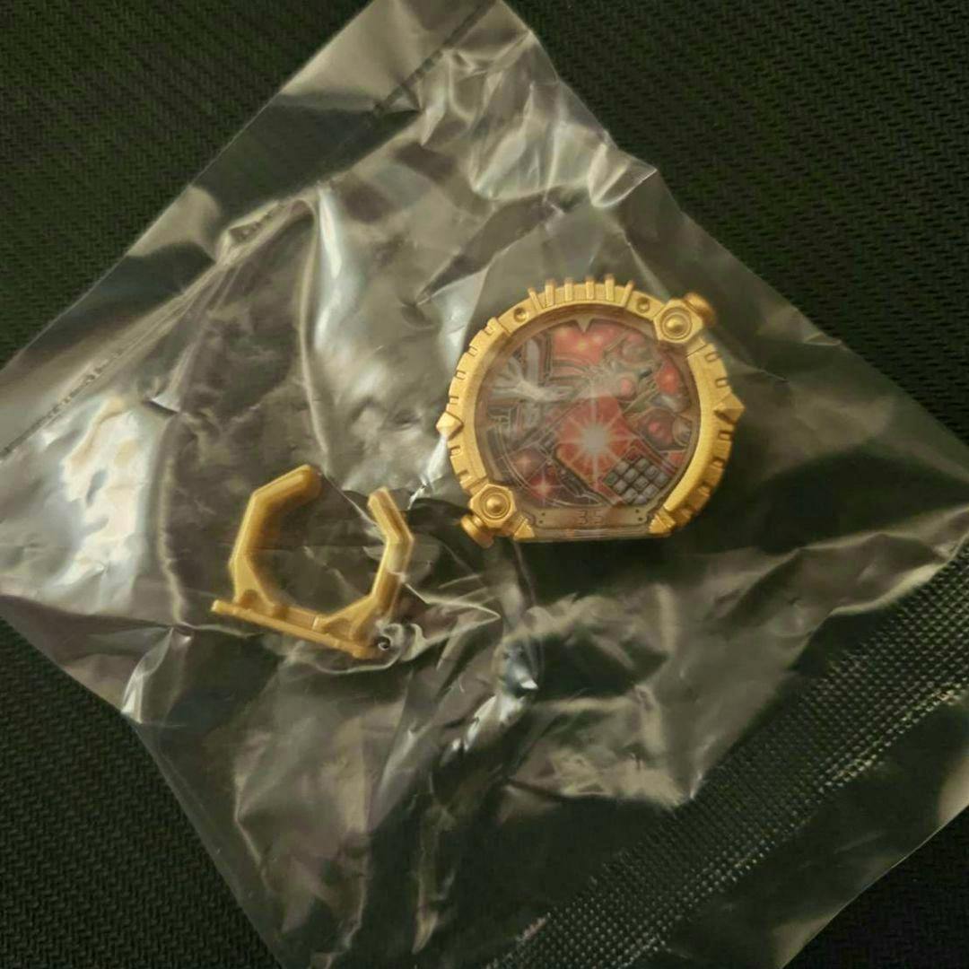 A gold-colored Sentai ring toy piece with a printed circular insert inside a clear plastic bag on a dark surface.