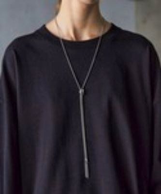 Model wearing a long thin chain necklace with two vertical bar pendants over a black top.