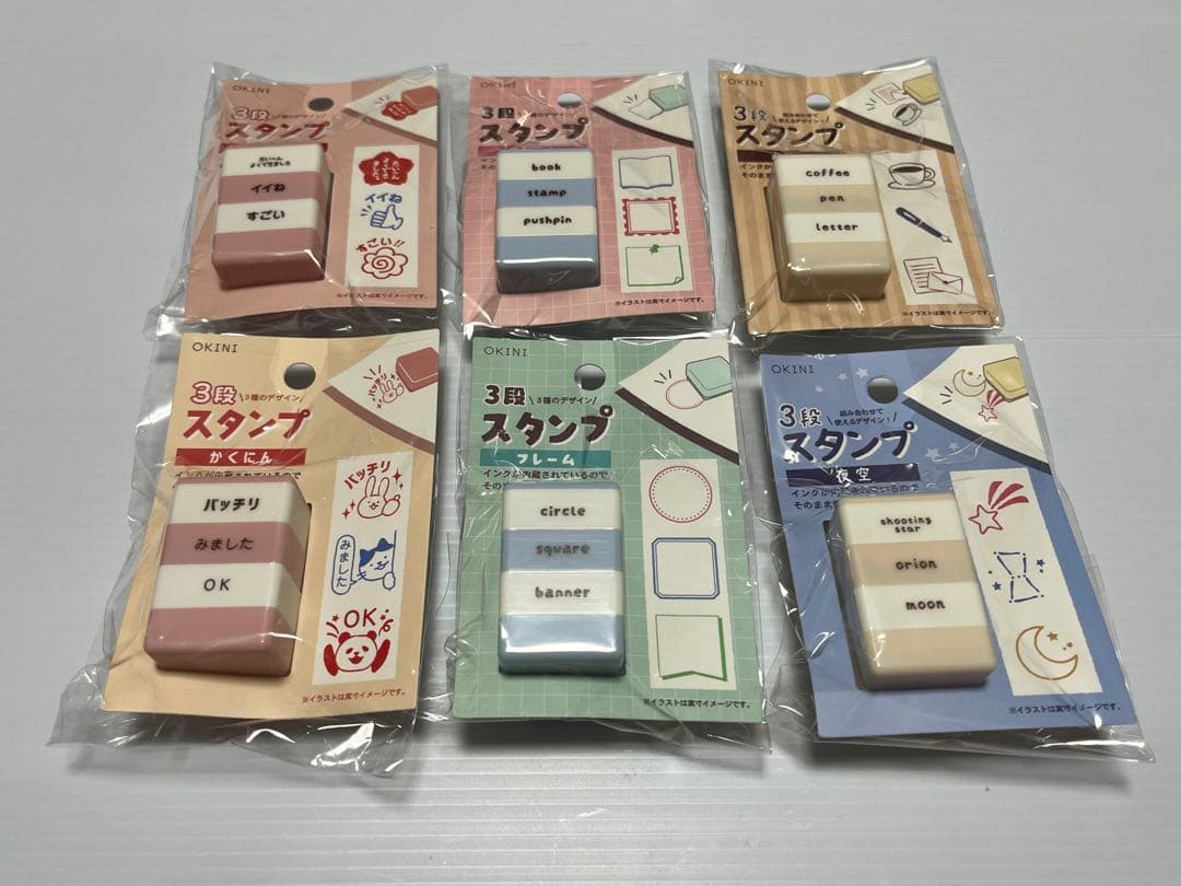 Six individually packaged plastic stamps on backing cards, arranged in two rows of three on a white surface.