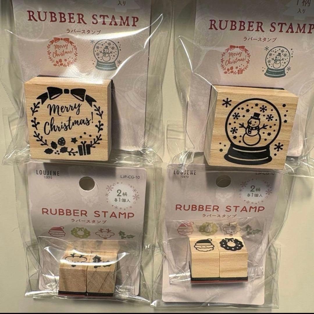 Four packaged wooden rubber stamps with Christmas designs: a wreath reading "Merry Christmas", a snow-globe with a snowman, and two smaller stamps in the lower row.