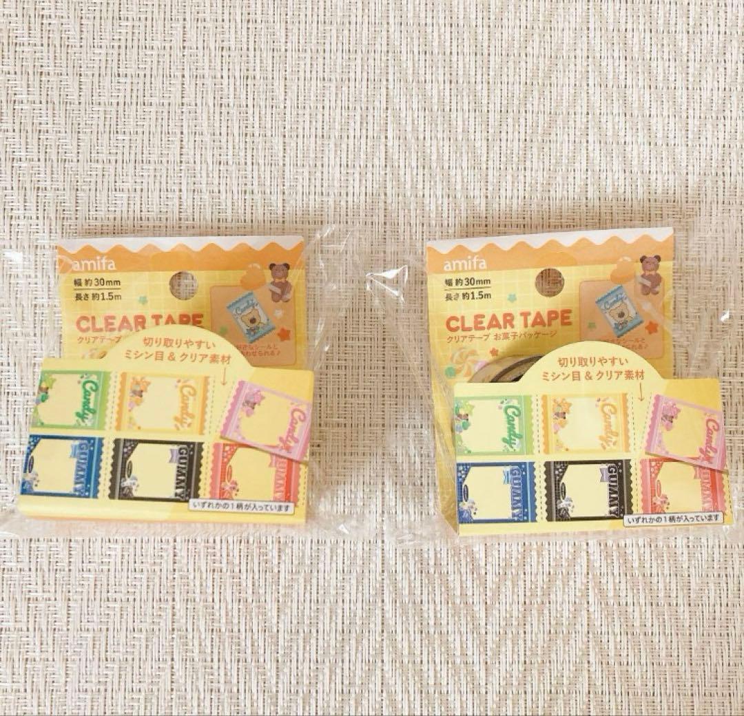 Two packaged clear tapes with candy-themed packaging shown side by side on a light fabric background.