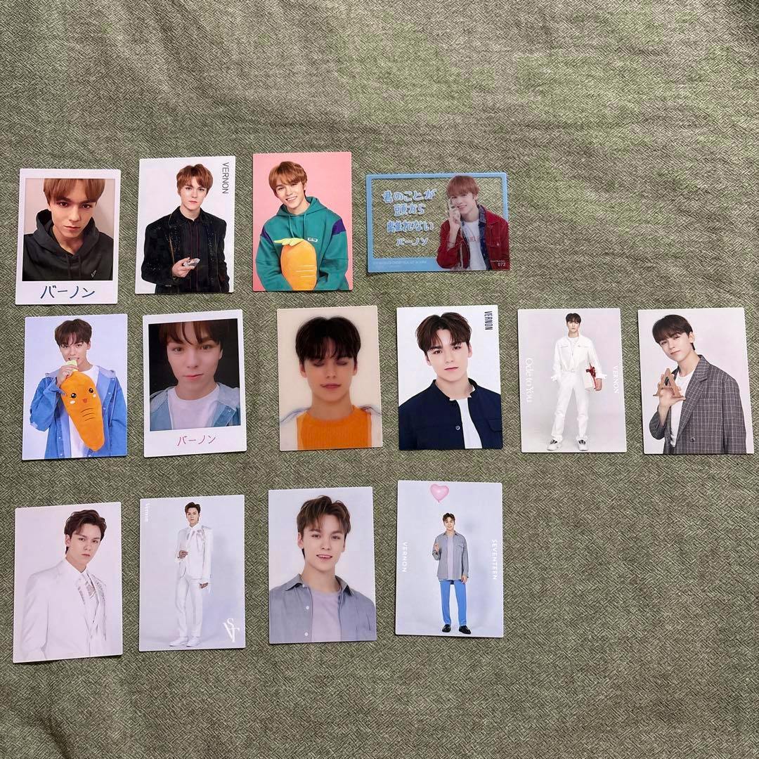 Fourteen SEVENTEEN Vernon photocards laid out on a textured fabric background showing various front designs.