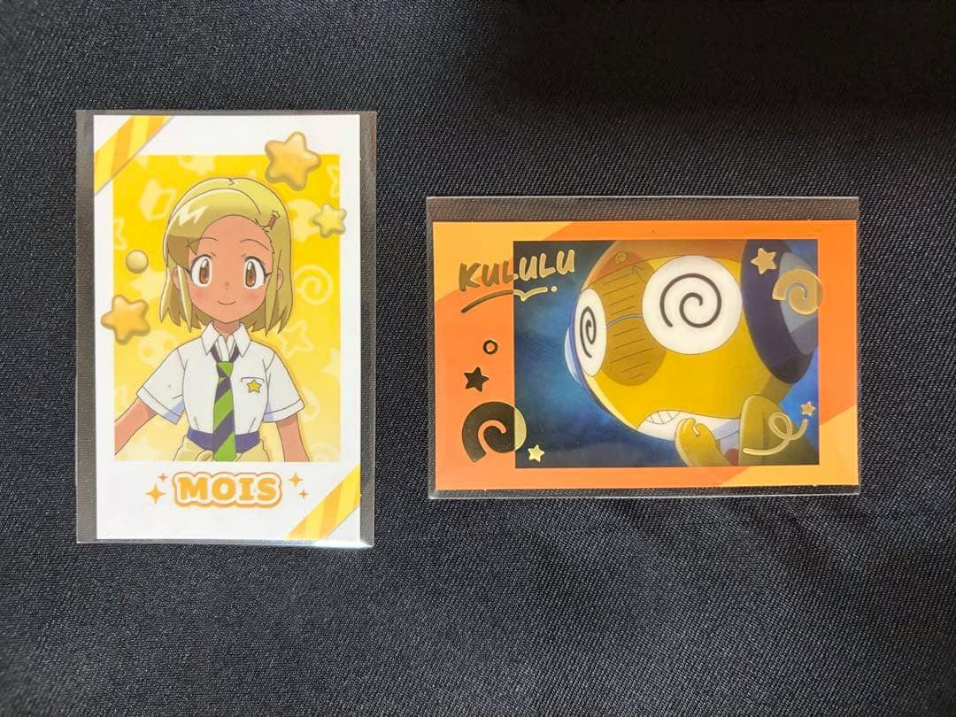 Two sleeved photocard portraits for ケロロ軍曹 laid on black fabric, one showing Kururu and one showing a female character.
