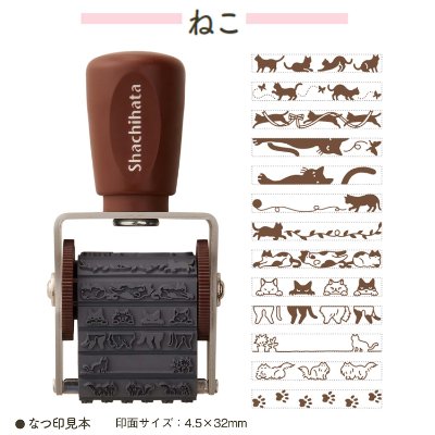 Shachihata rotating decoration stamp with a brown handle, visible rubber cat-pattern bands, and sample stamped designs.