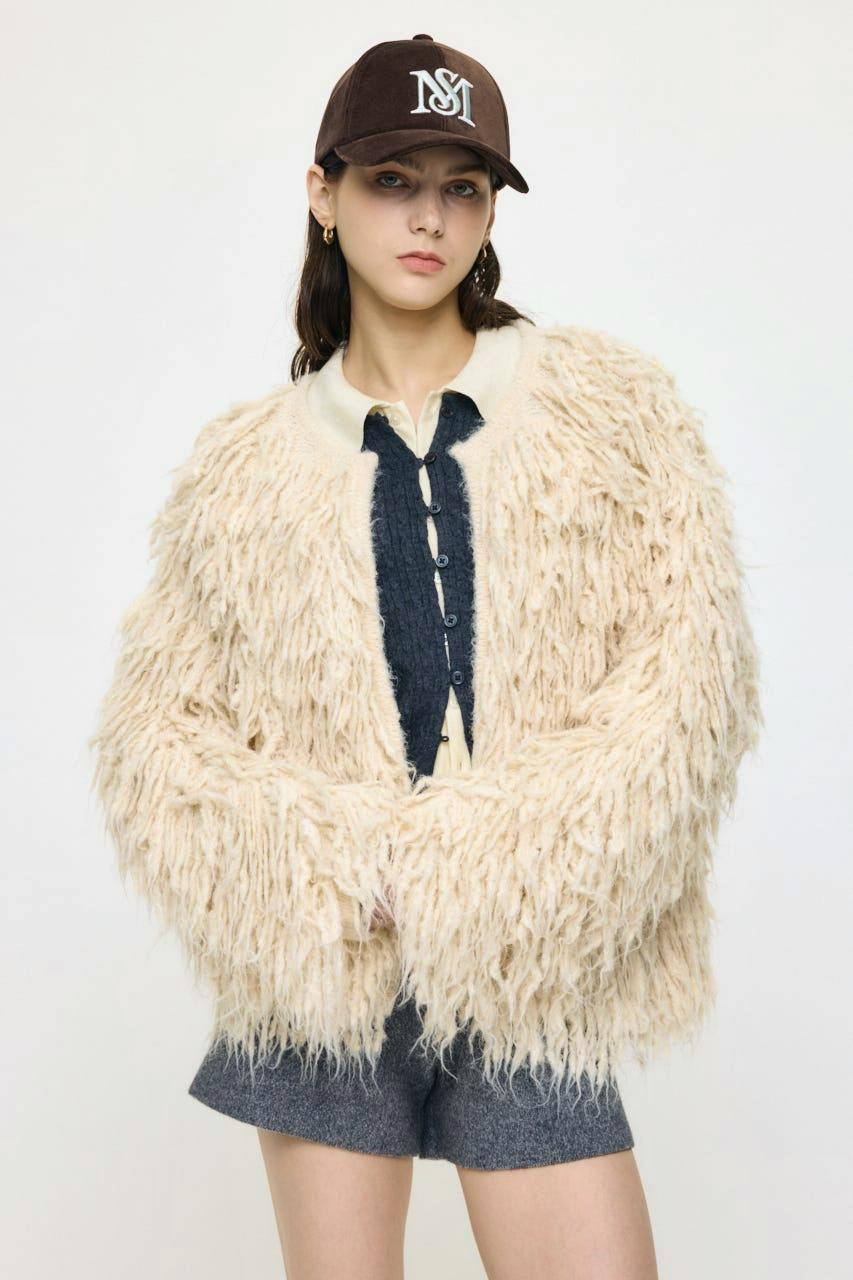 A model wearing the shaggy feather cardigan over layered clothing against a plain background.