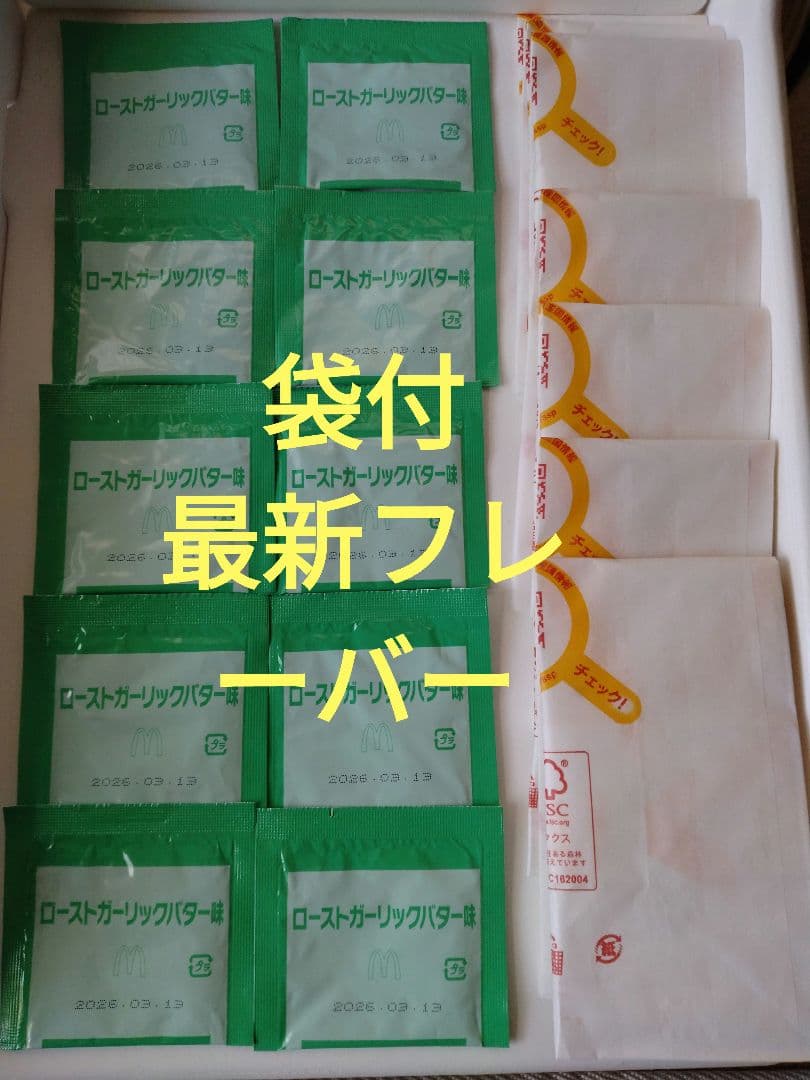 Green roasted-garlic-butter seasoning sachets and white Shaka Shaka Potato paper bags arranged together on a tray.