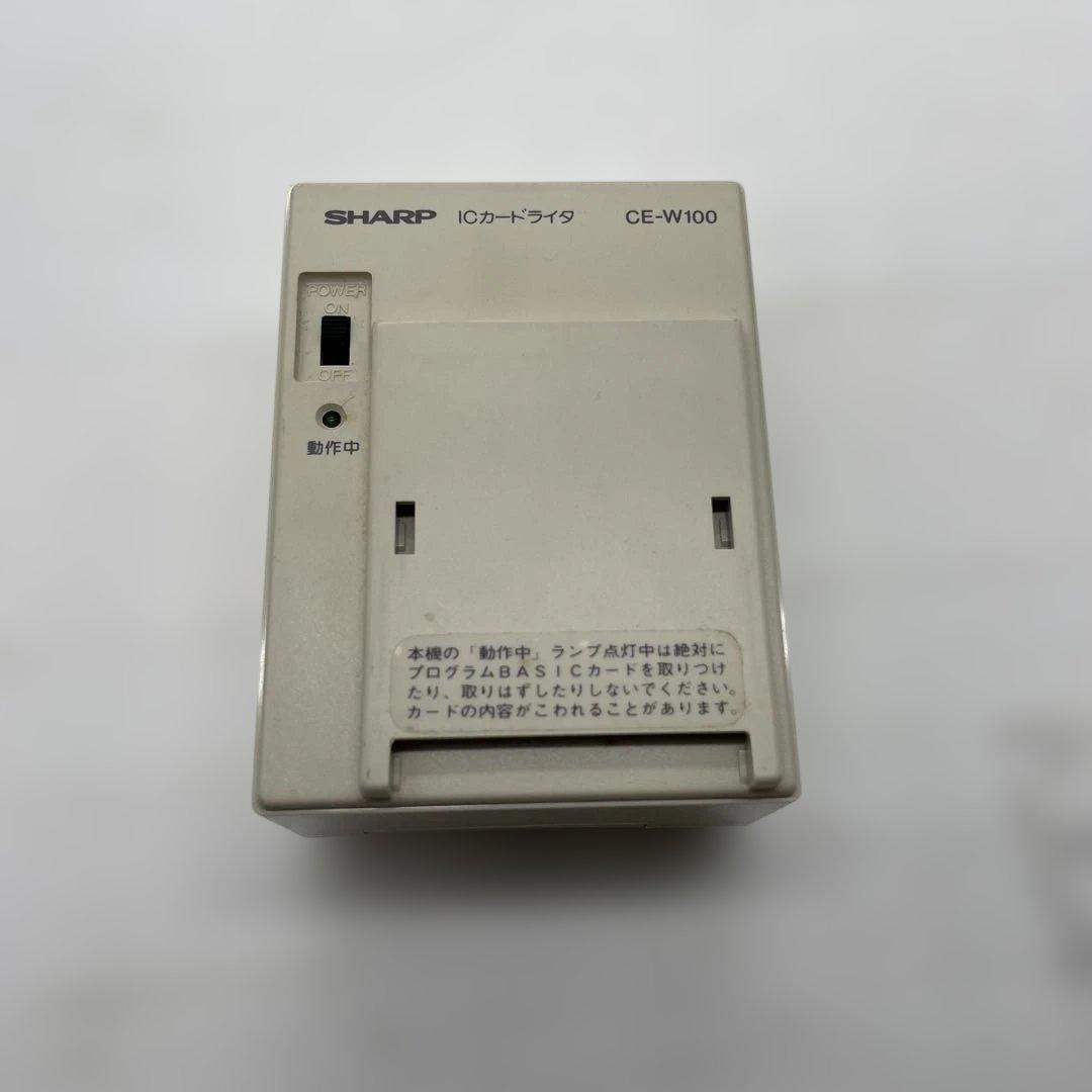 Top view of the SHARP ICカードライタ CE-W100 external IC card reader, showing the card slot, a small indicator, and model labeling.