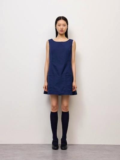 Front view of a navy sleeveless women's polyester dress worn by a model against a plain wall.