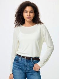 Female model wearing a white sheer long-sleeve rayon T-shirt paired with jeans, front view.